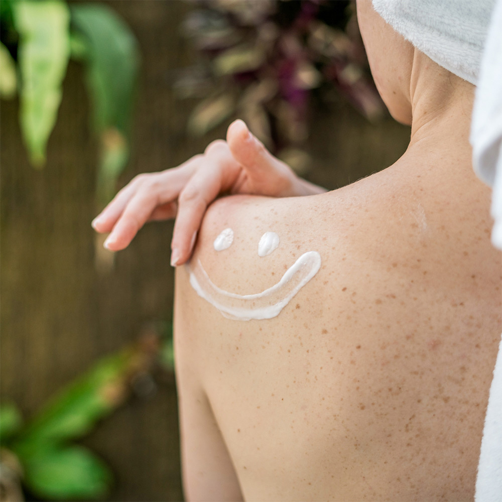 Bodylotion XL Aloe Vera Frauenschulter mit Smiley aus Bodylotion auf der Haut