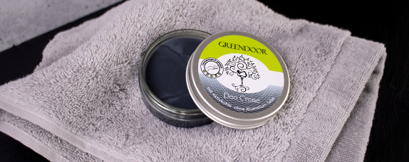 Dose mit GREENDOOR Fußcreme, geöffnet auf einem grauen Handtuch